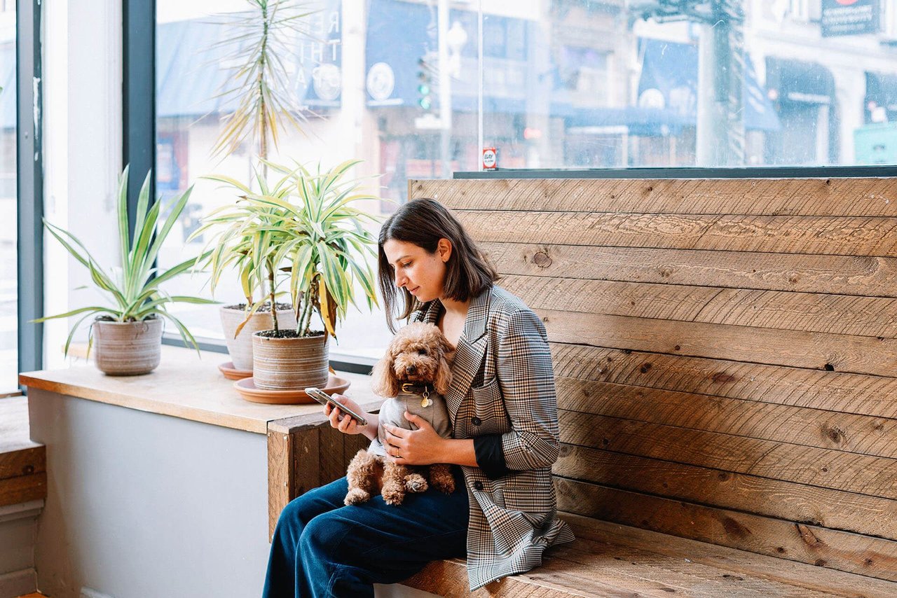 Woman using the Tigerhall app while sitting with her dog